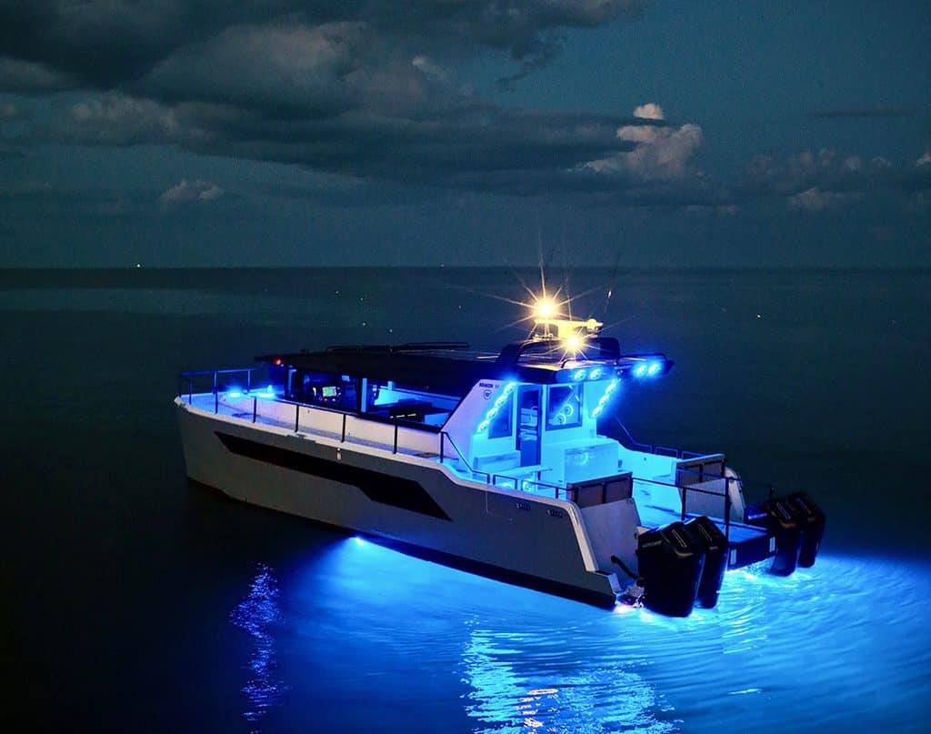 The 55-foot Super Kraken catamaran illuminated in blue on the water at night